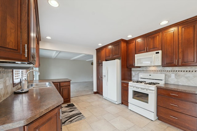 kitchen with dark countertops, white appliances, a sink, and backsplash