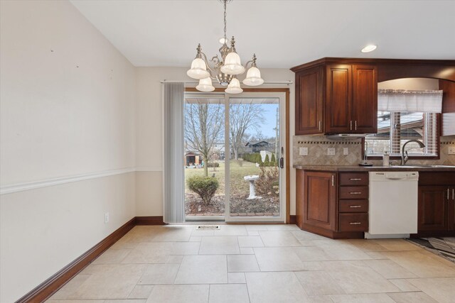 kitchen featuring white dishwasher, a sink, baseboards, backsplash, and an inviting chandelier