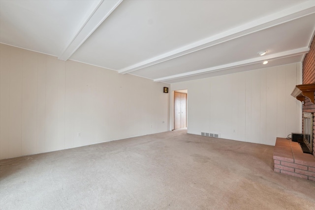 unfurnished living room featuring carpet floors, beam ceiling, a brick fireplace, and visible vents