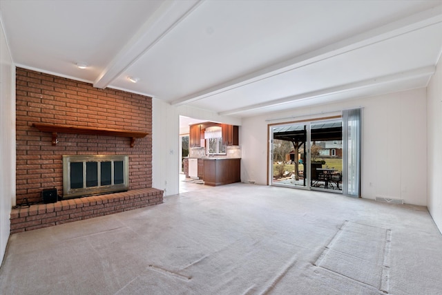 unfurnished living room with visible vents, a fireplace, light carpet, and beamed ceiling