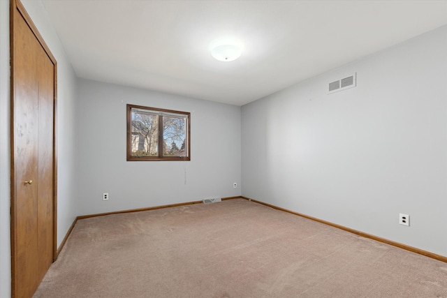 spare room featuring baseboards, visible vents, and light colored carpet