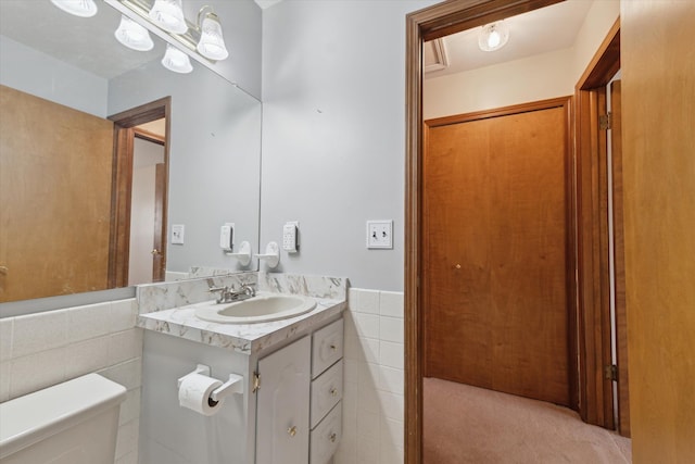 half bath featuring toilet, vanity, and tile walls