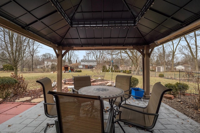 view of patio / terrace featuring a gazebo, a storage unit, fence, outdoor dining area, and an outdoor structure