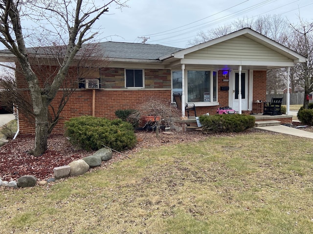 ranch-style house featuring a porch, a front yard, brick siding, and roof with shingles