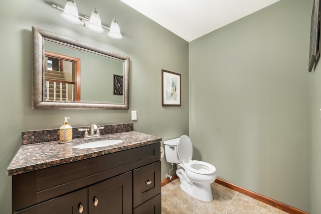 bathroom with toilet, tile patterned floors, baseboards, and vanity