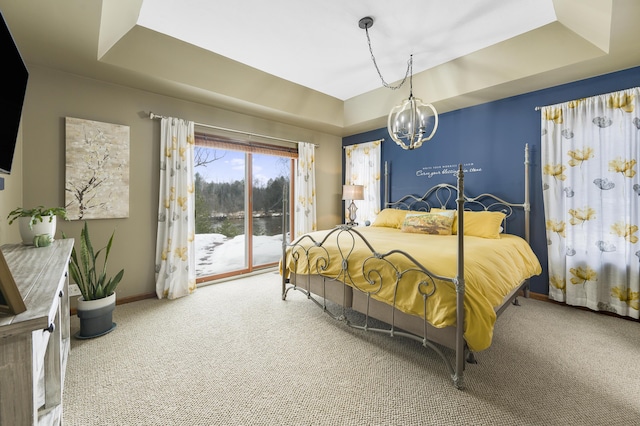 carpeted bedroom featuring access to exterior, a raised ceiling, baseboards, and an inviting chandelier