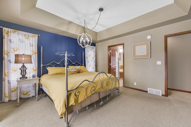 carpeted bedroom with a tray ceiling, visible vents, an inviting chandelier, connected bathroom, and baseboards