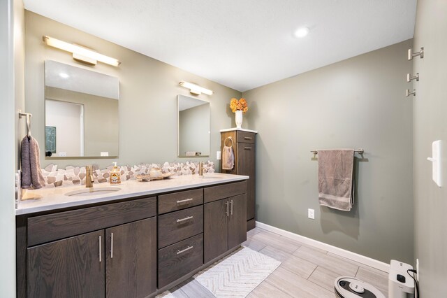 full bathroom with double vanity, baseboards, and a sink