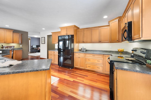 kitchen featuring light wood-style flooring, recessed lighting, black appliances, brown cabinetry, and dark countertops