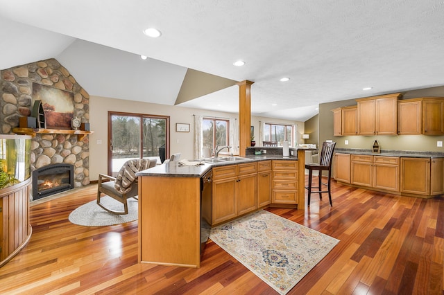 kitchen featuring lofted ceiling, a fireplace, a sink, black dishwasher, and open floor plan