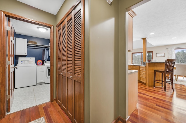 hallway featuring a textured ceiling, separate washer and dryer, recessed lighting, and light wood-style floors