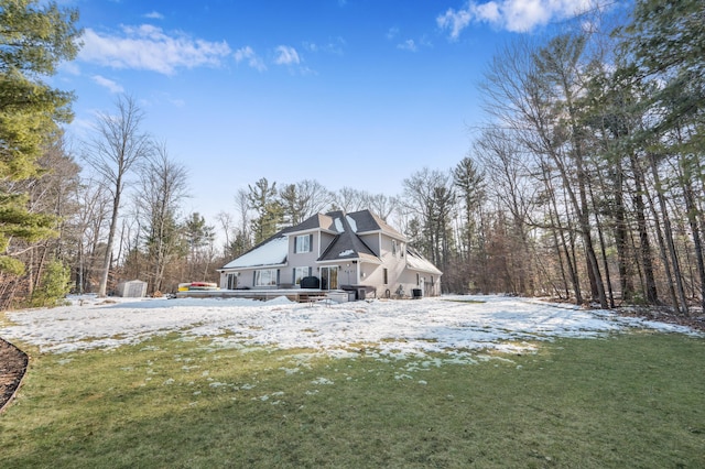 snow covered rear of property featuring a wooden deck and a yard