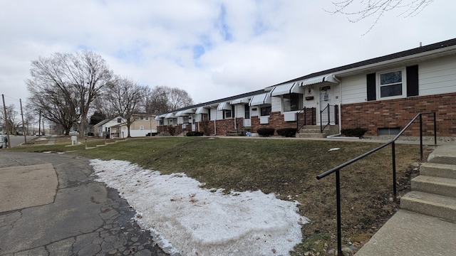 exterior space featuring brick siding, a front lawn, and a residential view