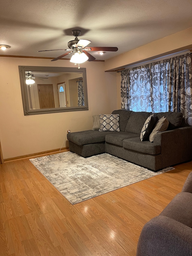 living room featuring a textured ceiling, ceiling fan, wood finished floors, and baseboards