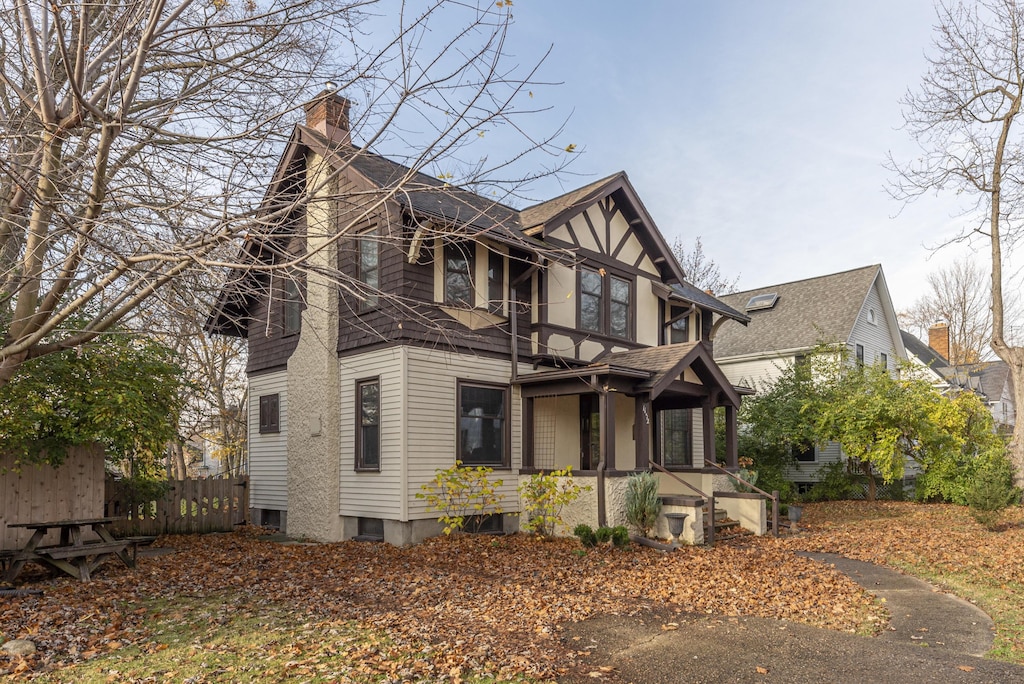 view of front of home featuring a porch, a chimney, and fence