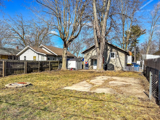 view of yard featuring an outbuilding, a patio, a storage shed, and a fenced backyard