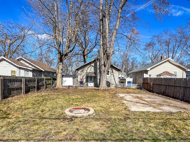 view of yard with an outdoor fire pit, a fenced backyard, and an outdoor structure