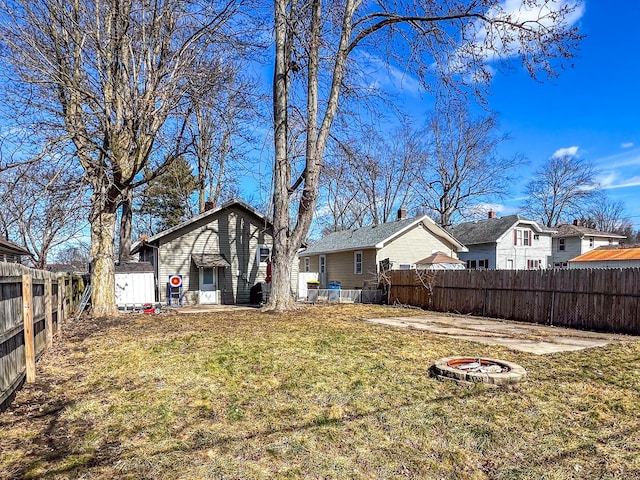 view of yard with an outdoor fire pit, a fenced backyard, and a residential view