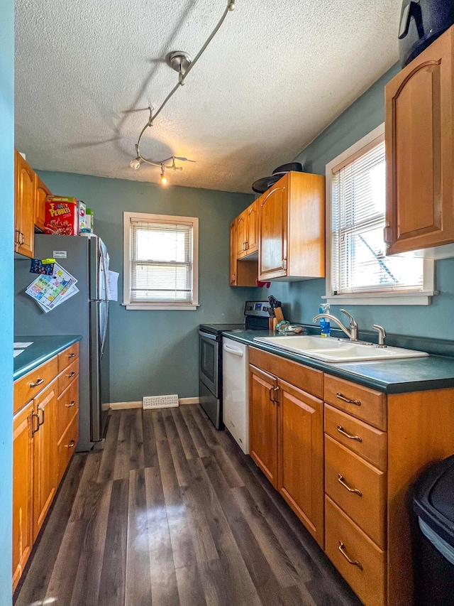 kitchen featuring dark wood-style flooring, a sink, baseboards, freestanding refrigerator, and dishwasher