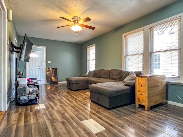 living room featuring a textured ceiling, dark wood finished floors, a ceiling fan, and baseboards