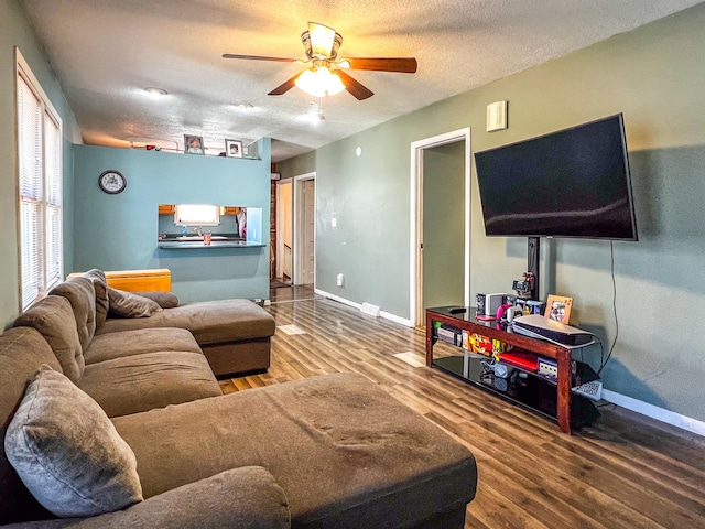 living room with a ceiling fan, a textured ceiling, baseboards, and wood finished floors