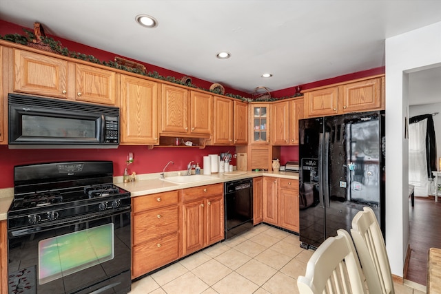 kitchen featuring recessed lighting, light countertops, light tile patterned flooring, a sink, and black appliances