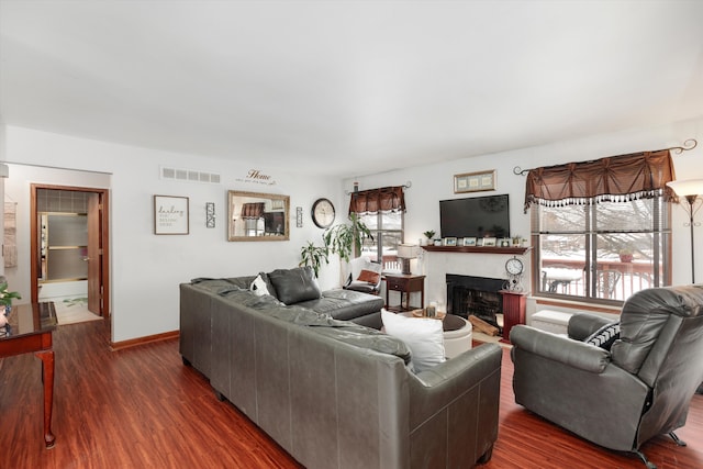 living room with dark wood-type flooring, visible vents, a fireplace, and baseboards