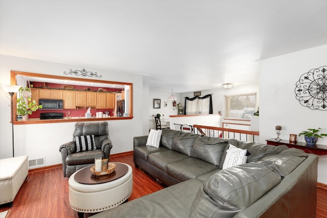 living area with baseboards, visible vents, and wood finished floors