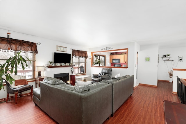 living area with a fireplace, baseboards, and wood finished floors