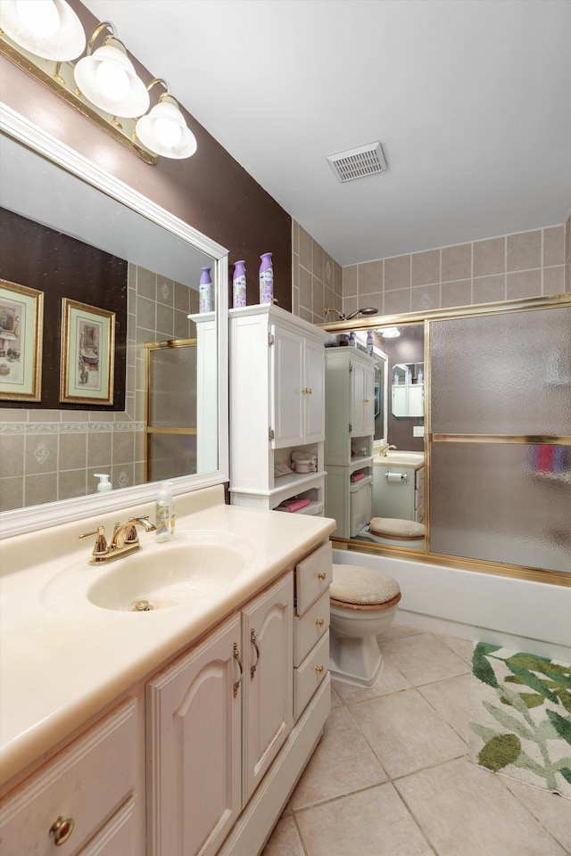 full bath featuring tile patterned flooring, toilet, vanity, visible vents, and combined bath / shower with glass door