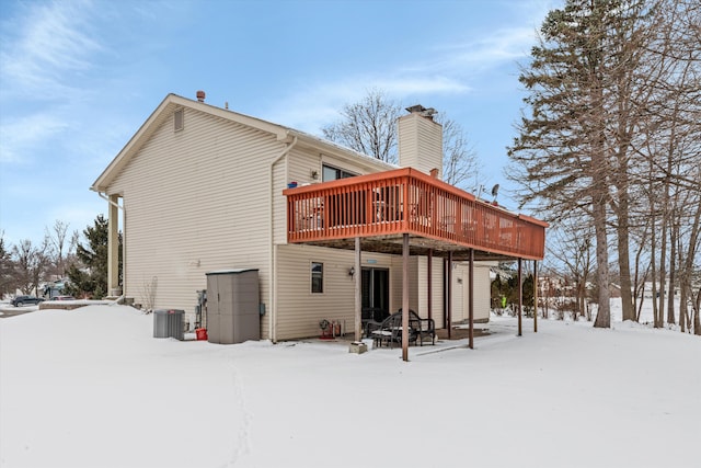 snow covered property featuring cooling unit and a wooden deck