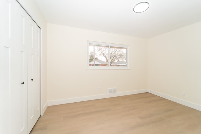 unfurnished bedroom with baseboards, a closet, visible vents, and light wood-style floors