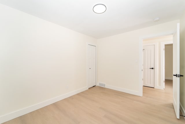 unfurnished room featuring light wood-type flooring, visible vents, and baseboards