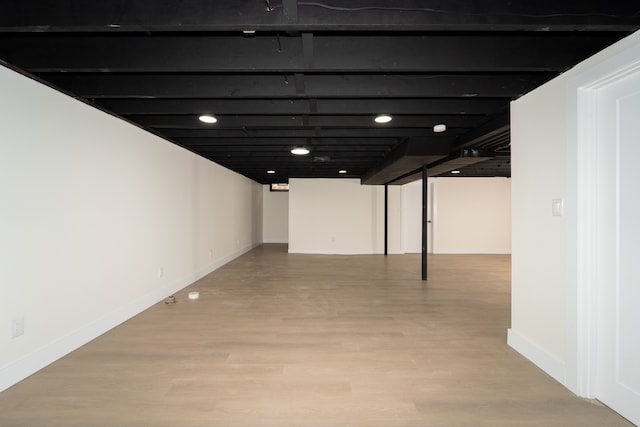 finished basement featuring light wood-style flooring and baseboards