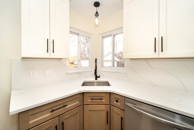 kitchen featuring light stone counters, tasteful backsplash, stainless steel dishwasher, white cabinets, and a sink