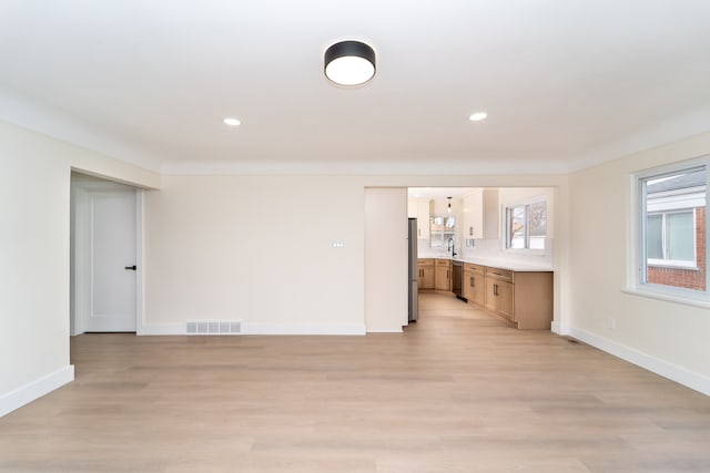 unfurnished living room featuring light wood-type flooring, visible vents, and baseboards