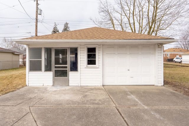 detached garage featuring fence and concrete driveway