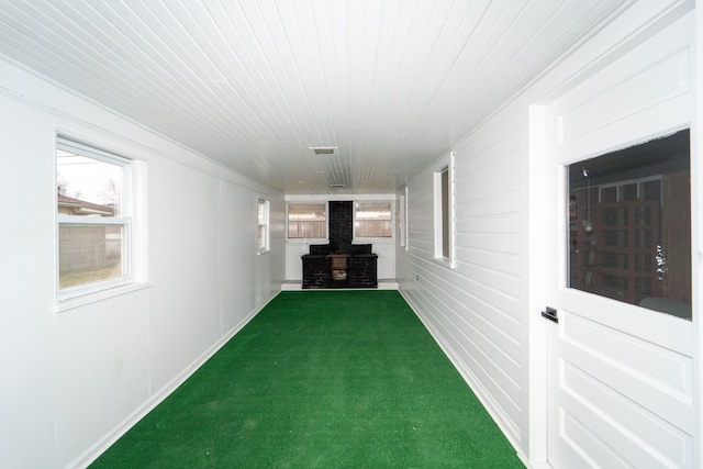 interior space with a wood stove, carpet, and baseboards