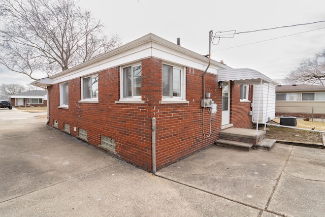 view of property exterior with brick siding, fence, and central air condition unit