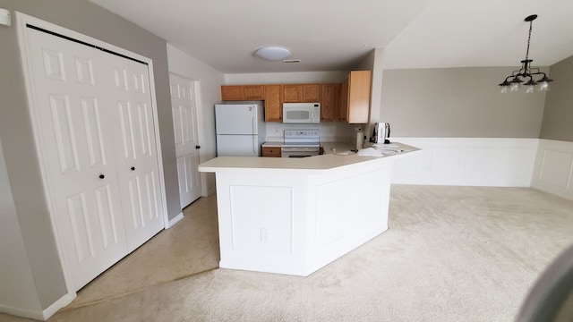 kitchen with a wainscoted wall, brown cabinets, decorative light fixtures, white appliances, and light countertops