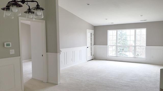 unfurnished room featuring visible vents, carpet, wainscoting, and vaulted ceiling