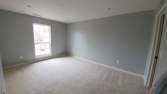 spare room featuring visible vents, light colored carpet, and baseboards