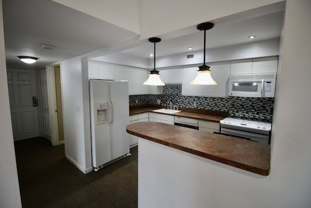 kitchen with dark countertops, white appliances, white cabinets, and a sink