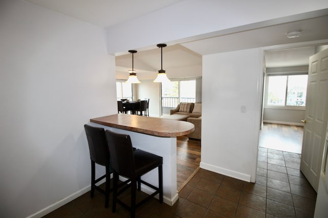 kitchen featuring a peninsula, a breakfast bar, and baseboards