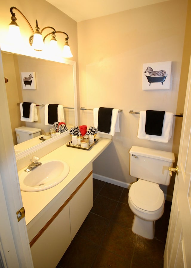 bathroom featuring toilet, vanity, baseboards, and tile patterned floors