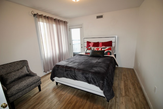 bedroom with wood finished floors, visible vents, and baseboards