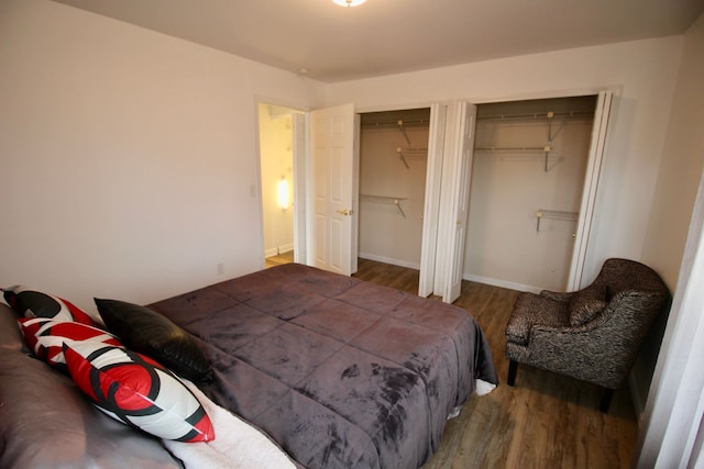 bedroom featuring wood finished floors, baseboards, and two closets