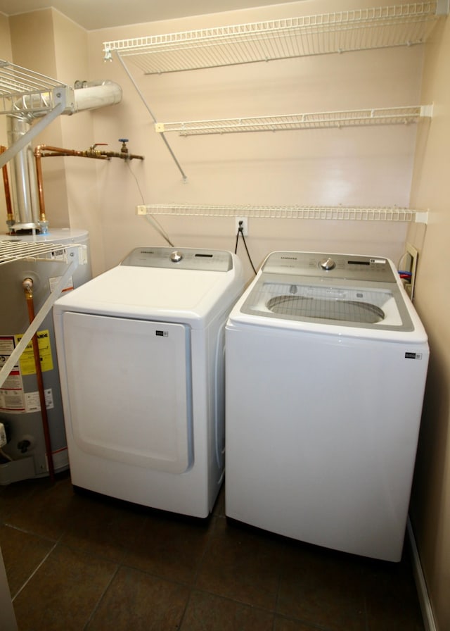 washroom with water heater, laundry area, dark tile patterned flooring, and independent washer and dryer