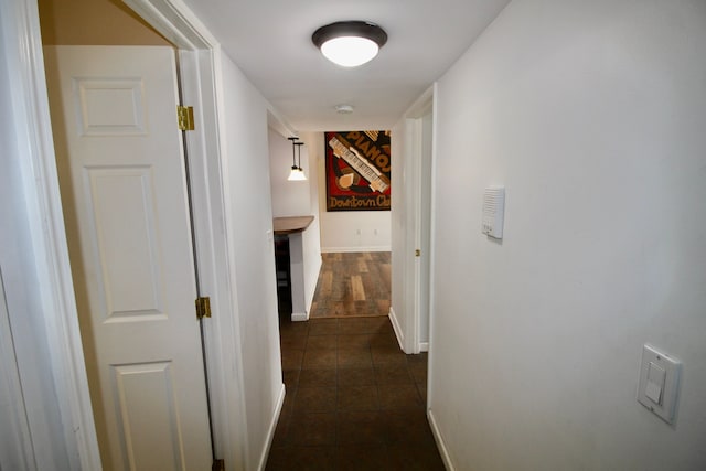 hall featuring dark tile patterned floors and baseboards