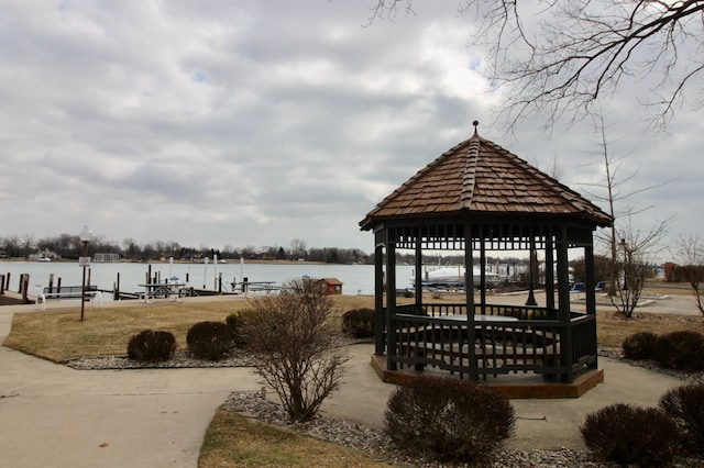 view of community with a dock, a water view, and a gazebo